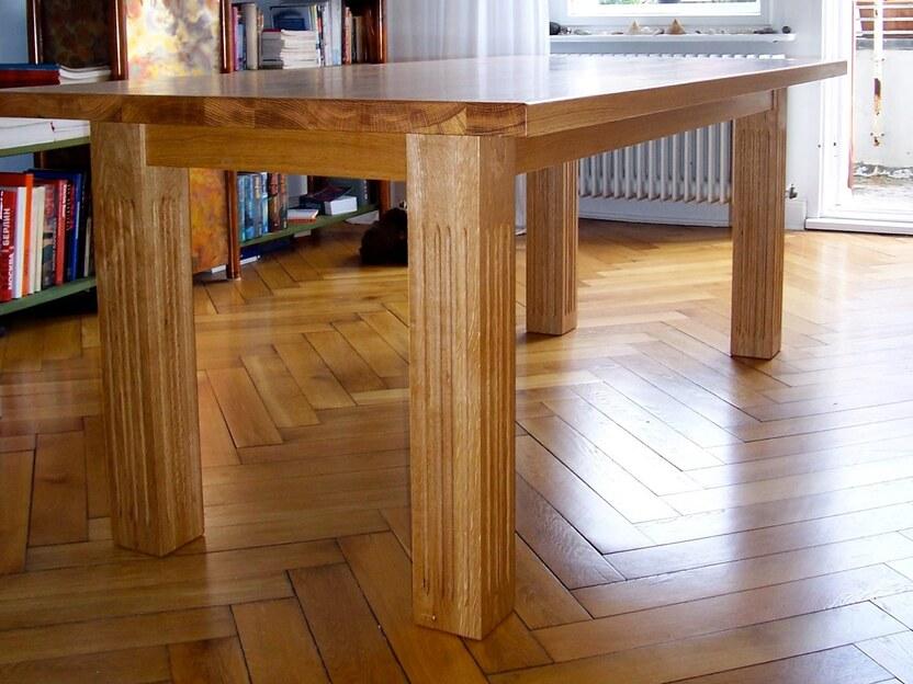 Esstisch Eiche massiv Massiver Esstisch aus heller Eiche mit klaren Linien steht in einem hellen Raum mit Parkettboden und großen Fenstern.