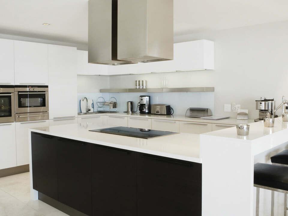 Moderne Küche nach Maß mit Kochinsel und Edelstahlgeräten Stilvolle Küche nach Maß in Schwarz-Weiß-Design mit großzügiger Kochinsel, Edelstahlgeräten und eleganter Beleuchtung.