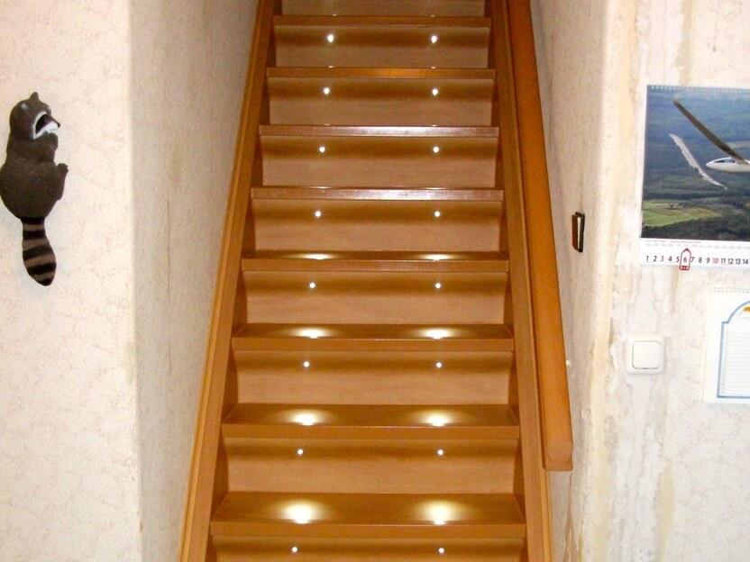 Holztreppe mit LED-Beleuchtung Gerade Holztreppe aus hellem Holz mit integrierter LED-Stufenbeleuchtung in einem Hausflur.