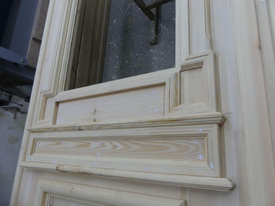 Detailansicht einer restaurierten Holztür mit aufwendig profilierten Rahmen und glatter Holzoberfläche.