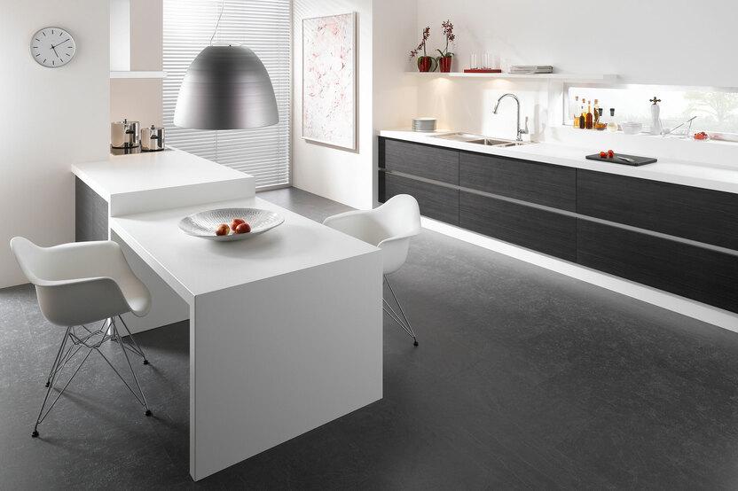 Impression einer einzeiligen Küchengestaltung in schwarz-weiß mit Esstisch für Zwei