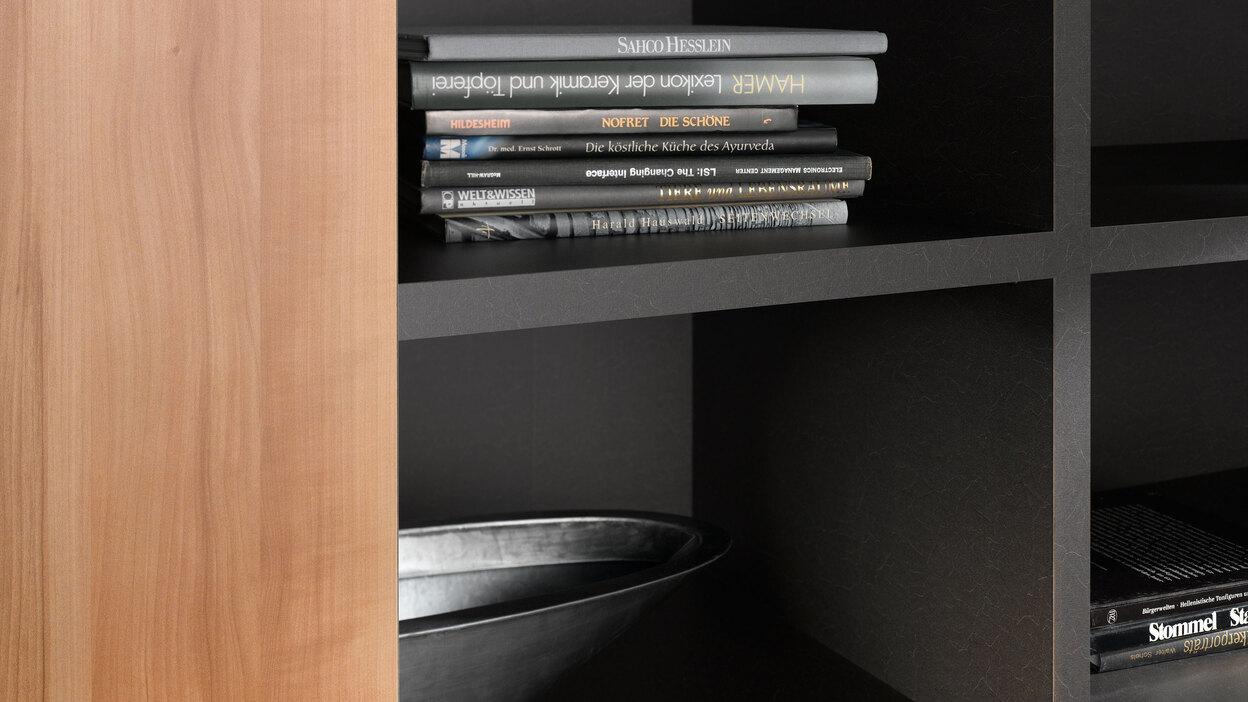 Detailaufnahme eines dunklen Regals Detailaufnahme eines schwarz lackierten Regals mit Büchern und Schale in Kombination mit naturbelassenem Holz.