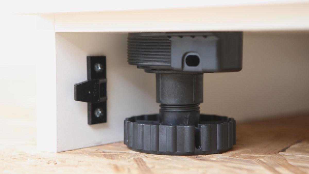 Detailaufnahme eines verstellbaren Sockels Detailaufnahme eines verstellbaren schwarzen Bodensockels mit Schraubmechanismus